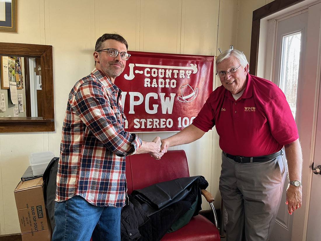 WPGW owner Rob Weaver (right) and owner-to-be Mark King shake hands this week while meeting at the radio station office west of Portland. Final approval of the sale from the Federal Communications Commission is expected this spring. Weaver plans to stay on to help with the transition process, saying he’d like to be retired within two years. (The Commercial Review/Ray Cooney)