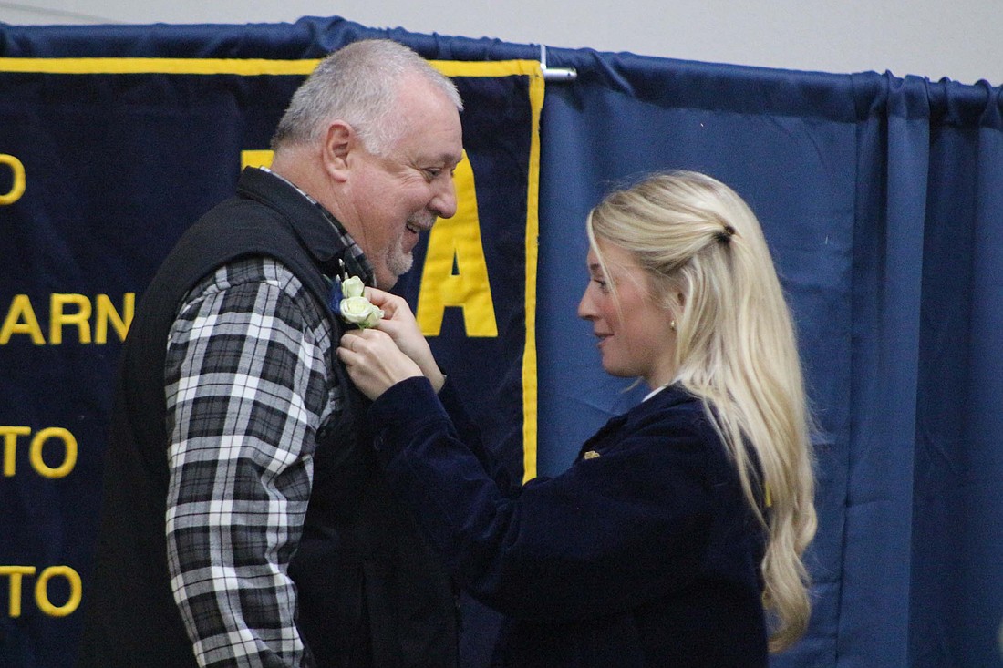 Jay County FFA vice president Gretchen Link pins a boutonniere to Chris Krieg’s vest Friday during the annual banquet at Jay County High School. Krieg, a graphic arts teacher at the high school, was inducted into Jay County FFA’s Hall of Fame. (The Commercial Review/Bailey Cline)