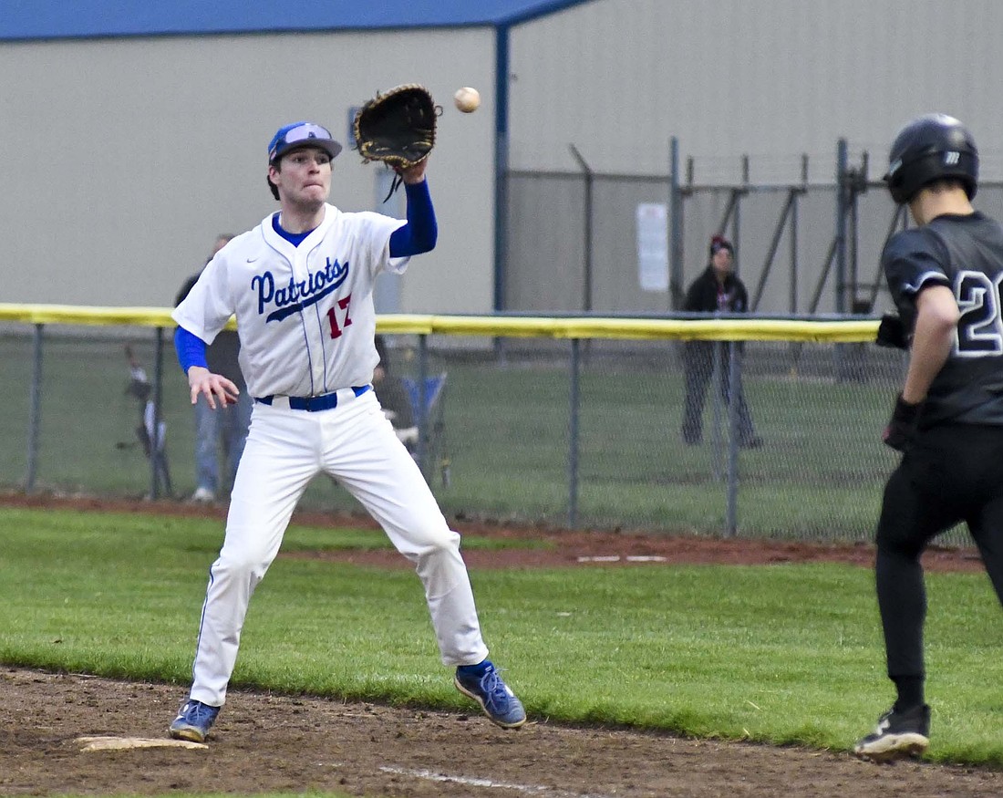 Jay County High School first baseman Joe Geesaman receives a throw from catcher Drew Schemenaur to get out Malakai Luthy on a dropped third strike during the Patriots 6-1 loss to Eastbrook in Friday’s season opener. Only one of the Panthers’ runs were earned as JCHS committed eight errors. (The Commercial Review/Andrew Balko)