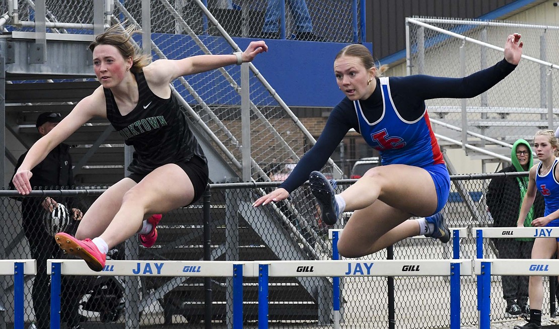 Jay County High School’s Morgan DeHoff keeps the 100-meter hurdles close with Analyn Hymas of Yorktown during a tri-meet on Thursday. Hymas beat DeHoff by 0.29 seconds in the race to help the Tigers beat host Jay County 71-53, while Delta lagged behind with 38 points. (The Commercial Review/Andrew Balko)