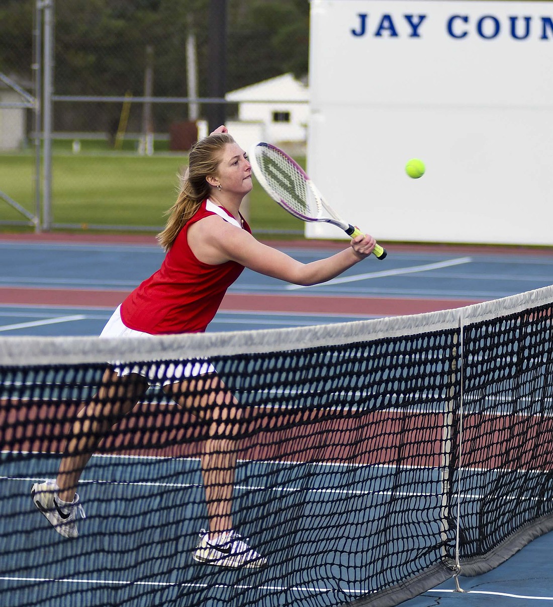 Jay County High School junior Faith Faulkner volleys a ball at the net during the third set of the No. 1 doubles match against Winchester on Monday. Faulkner along with Raylah Newton took down Brooklyn Friend and Addison Haney 6-1, 5-7, 7-5 to help the Patriots to a 4-1 win. (The Commercial Review/Andrew Balko)