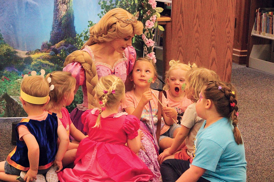 Rapunzel from Disney’s “Tangled” visited Jay County Public Library on Thursday. Pictured, Amara Eley of Portland (center) and other children gather around Rapunzel as she sings “I See the Light.” Festivities at the library included face painting, hair braiding, painting pictures, making paper lanterns and other movie-themed activities. (The Commercial Review/Bailey Cline)