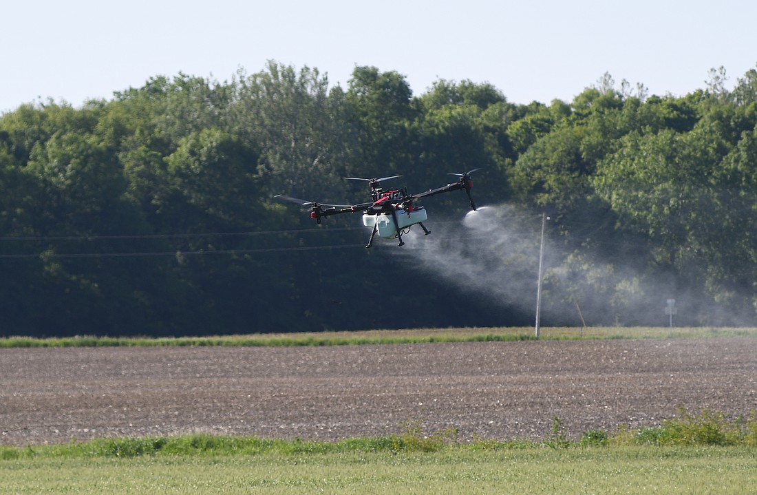 A drone operated by Josh Overman sprays fungicide on a field on the south side of Indiana 26 just east of county road 400 East on Saturday morning. The drone has a capacity of 18 gallons, which is enough to cover about 9 acres. (The Commercial Review/Ray Cooney)