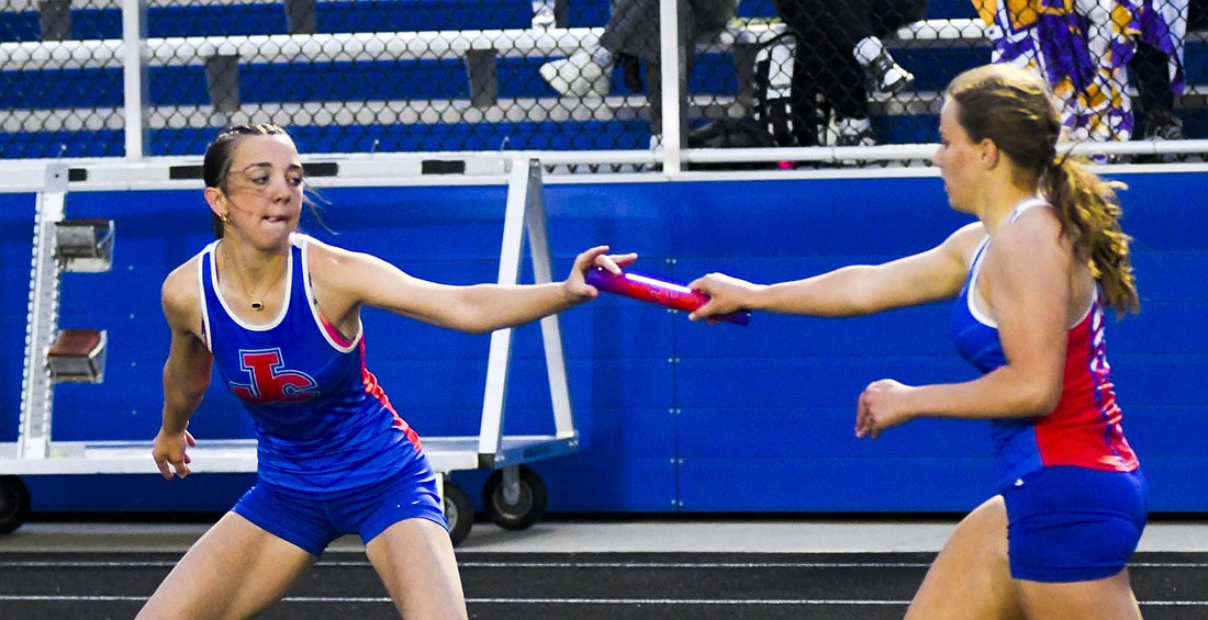 Jay County High School freshman Brooklynn Byrum hands the baton off to Payton Carpenter during the 4x400-meter relay at Carroll on Tuesday as part of the regional meet. While the relay ended up in 16th, both athletes competed in individual events as well, with Byrum earning 12th place in the 800 run and Carpenter finishing 14th in the 400 dash. (The Commercial Review/Andrew Balko)