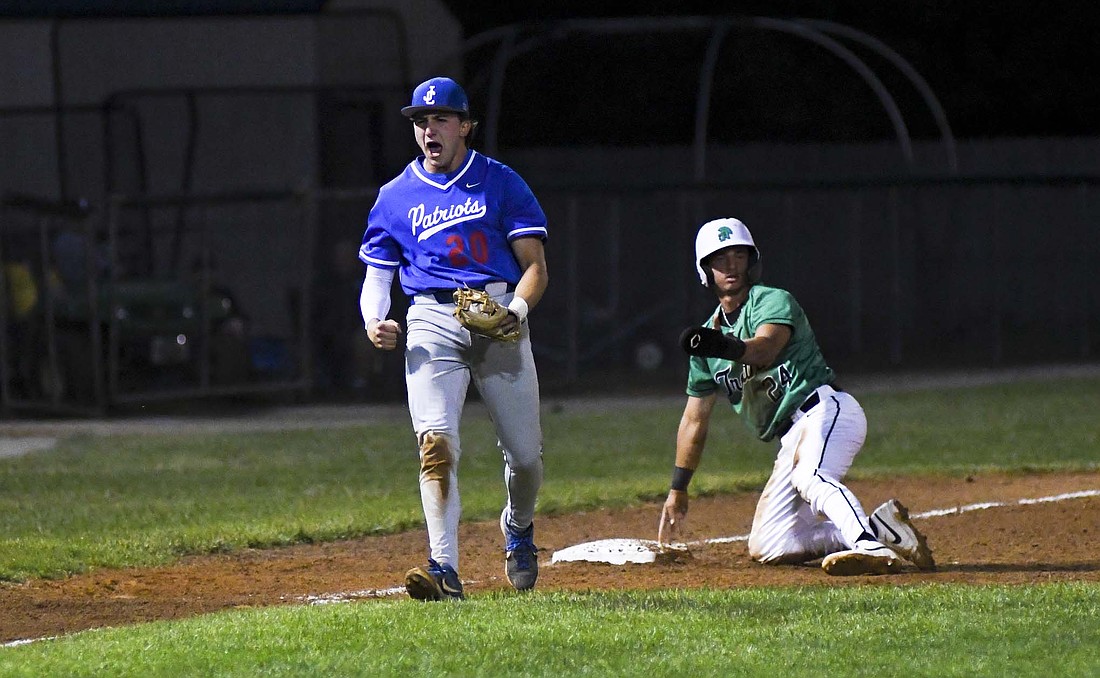 Jay County High School third baseman Carter Fugiett exclaims after Drew Schemenaur caught New Castle’s Jayden Sticco stealing the bag early in the Patriots’ 10-2, 12-inning win in the sectional opener at Yorktown on Wednesday. JCHS got five Trojans out on the base paths as Schemenaur caught three stealing, Kade Sommers picked off a runner and Joe Geesaman doubled up a runner at second base for a key defensive stop late in the game that ended at about 1 a.m. Thursday. (The Commercial Review/Andrew Balko)
