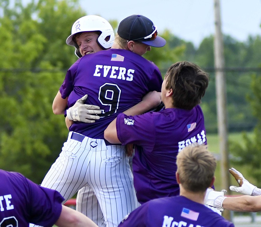 Gavin Evers, Caden Homan and the rest of the Fort Recovery High School baseball team begin to mob Colson Post (helmet) after he delivered the walk-off double that claimed the OHSAA Division VI Southwest 3 District title in the ninth inning at Houston. The win advances the Tribe to Tuesday's regional semifinal. (The Commercial Review/Andrew Balko)