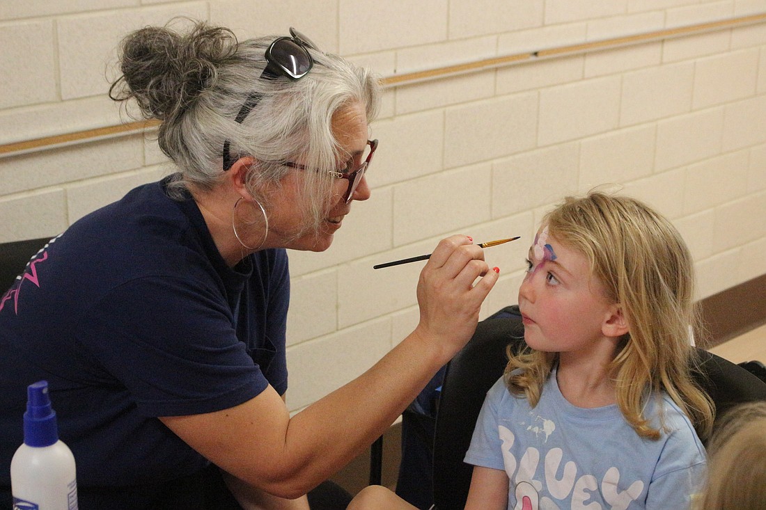 Tasha Weaver of Firefly Children and Family Alliance paints 4-year-old Evelyn Osterholt’s forehead Friday during the summer carnival at Westminster Preschool Jay County Early Learning Center in Portland. (The Commercial Review/Bailey Cline)