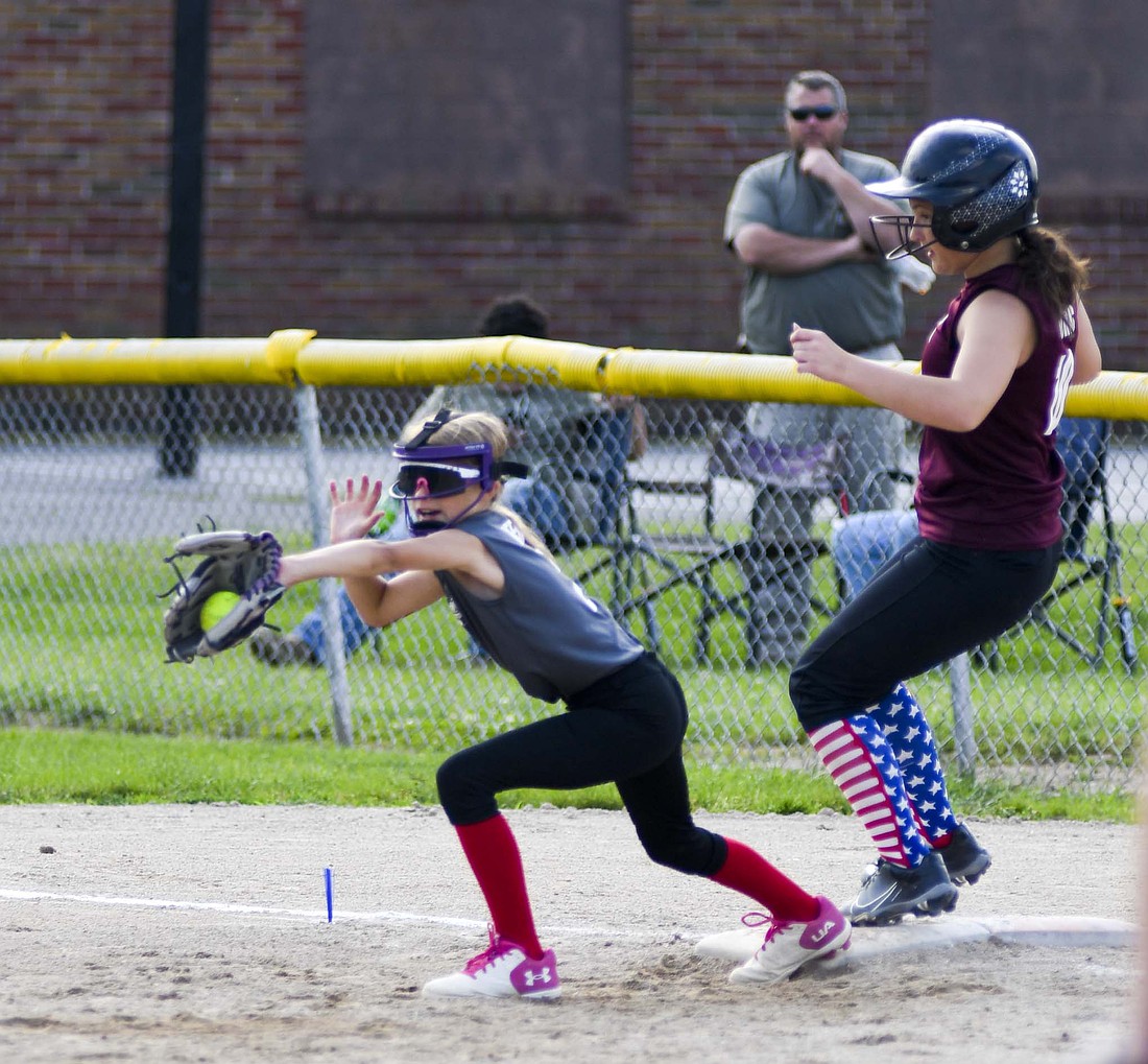 First baseman Alyvia Pfeifer of Crossroads FCU receives a throw as the batter from Fisher Meats reaches the base on Monday during Portland Junior League Minor softball. (The Commercial Review/Andrew Balko)