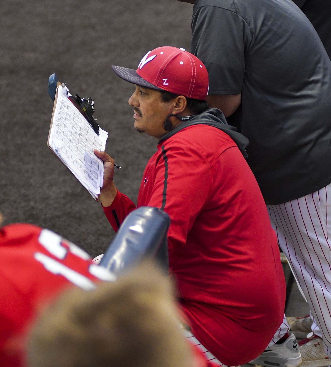 Jay County High School graduate and Wapahani assistant baseball coach Josh Shatto communicates what pitch to throw during the Raiders’ IHSAA Class 2A Semi-State final against No. 6 Boone Grove on Saturday. Wapahani won the opener 3-0 over host Oak Hill before ultimately falling short of a trip to state with a 9-2 loss to the Wolves. (The Commercial Review/Andrew Balko)