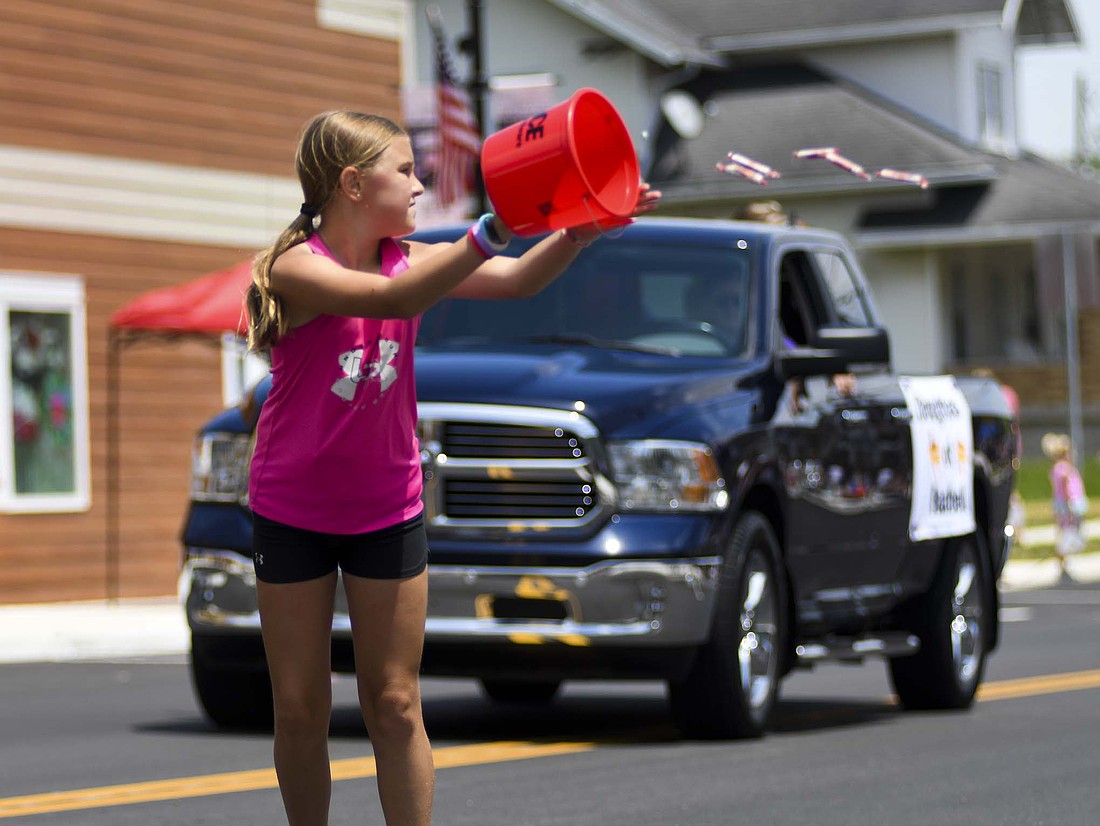 A participant in Sunday’s Fort Recovery Harvest Jubilee parade empties her bucket of candy while walking along Butler Street. The parade featured plenty of candy, classic cars, emergency responder vehicles and farm equipment as the annual festival came to a close. (The Commercial Review/Ray Cooney)