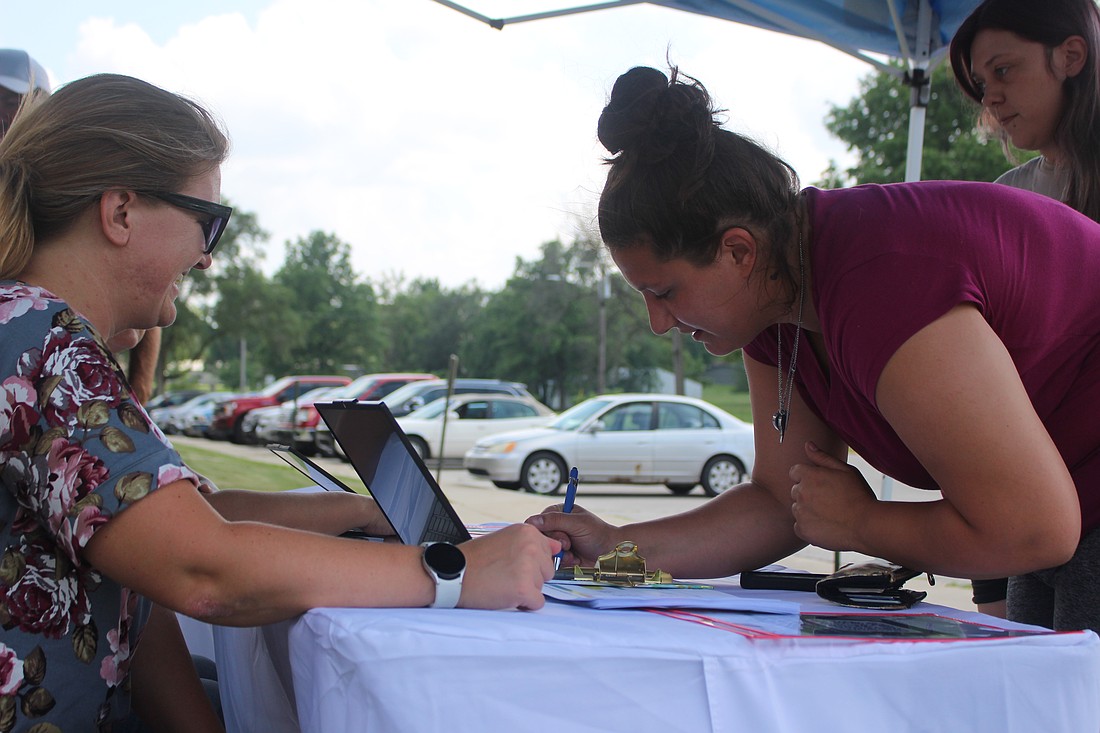 Save the Children Head Start hosted a community outreach event Wednesday outside West Jay Community Center in Dunkirk to gauge community members’ interest in a Dunkirk-based Head Start education program. Pictured above, a woman writes on the list for those interested in enrolling their children. (The Commercial Review/Bailey Cline)