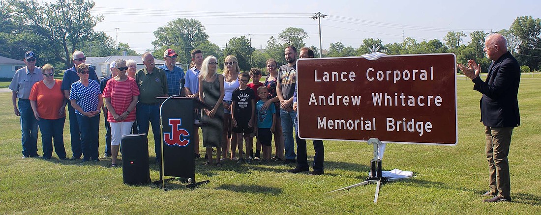 A sign indicating the dedication of the Indiana 67 bridge over the Salamonie River southwest of Jay County Junior-Senior High School was unveiled during a ceremony in front of the school Thursday morning. Whitacre died in military service on June 19, 2008, while serving in Afghanistan as part of the 2nd Battalion, 7th Marine Regiment, 1st Marine Division, 1 Marine Expeditionary Force, Twentynine Palms, California. (The Commercial Review/Ray Cooney)