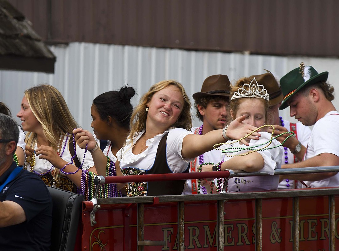 Members of the Swiss Days court toss beaded necklaces to the crowd during Saturday’s parade. Storms delayed the start of the parade by a half hour. (The Commercial Review/Ray Cooney)