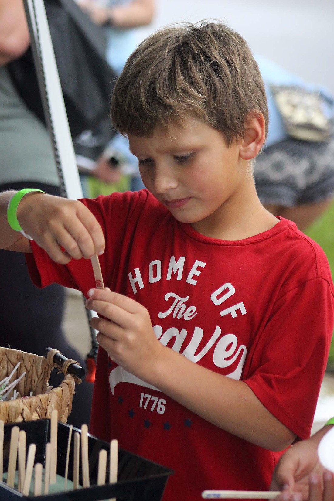 Adrian Nava, 7, Portland, picks a popsicle stick Thursday at the Adapt Ability Autism Services stand during the Back-to-School Bash at Jay County Public Library. (The Commercial Review/Bailey Cline)