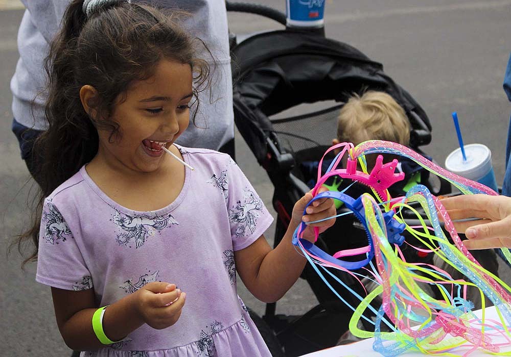 Evelyn Vargas, 6, Portland, grabs a headband from the Youth Service Bureau table Thursday during the Back-to-School Bash at Jay County Public Library. The first full day for teachers in Jay School Corporation is today, with students returning to their classrooms on Thursday. (The Commercial Review/Bailey Cline)