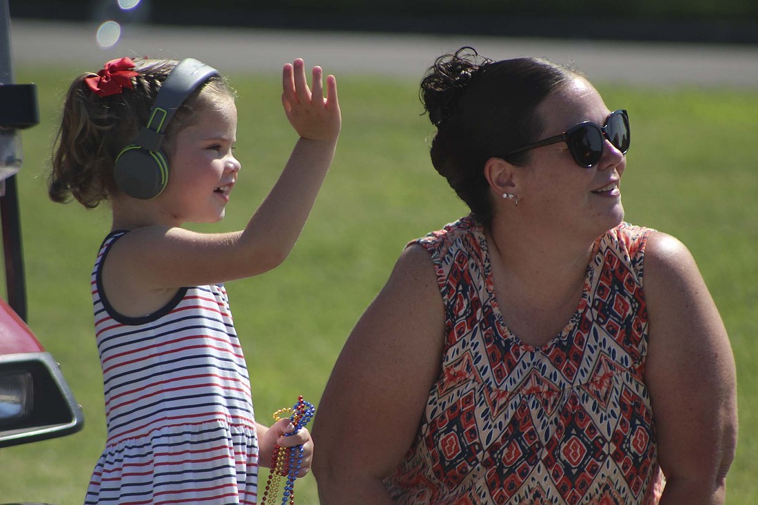 Layla J. Barlow, 3, waves with her mother Katie Ehrke at the Gas Boom Days parade on High Street in Redkey on Saturday. The annual Redkey festival kicked off with the parade and an extraction demonstration by Redkey Fire Department. (The Commercial Review/Bailey Cline)