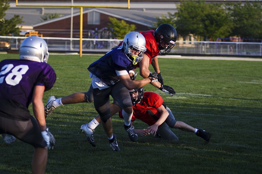 Running back Troy Post of the Fort Recovery High School football team splits a pair of defenders during Friday’s scrimmage against Indian Lake. The Tribe opens the season on Aug. 22 with a match against Ponitz. (The Commercial Review/Ray Cooney)
