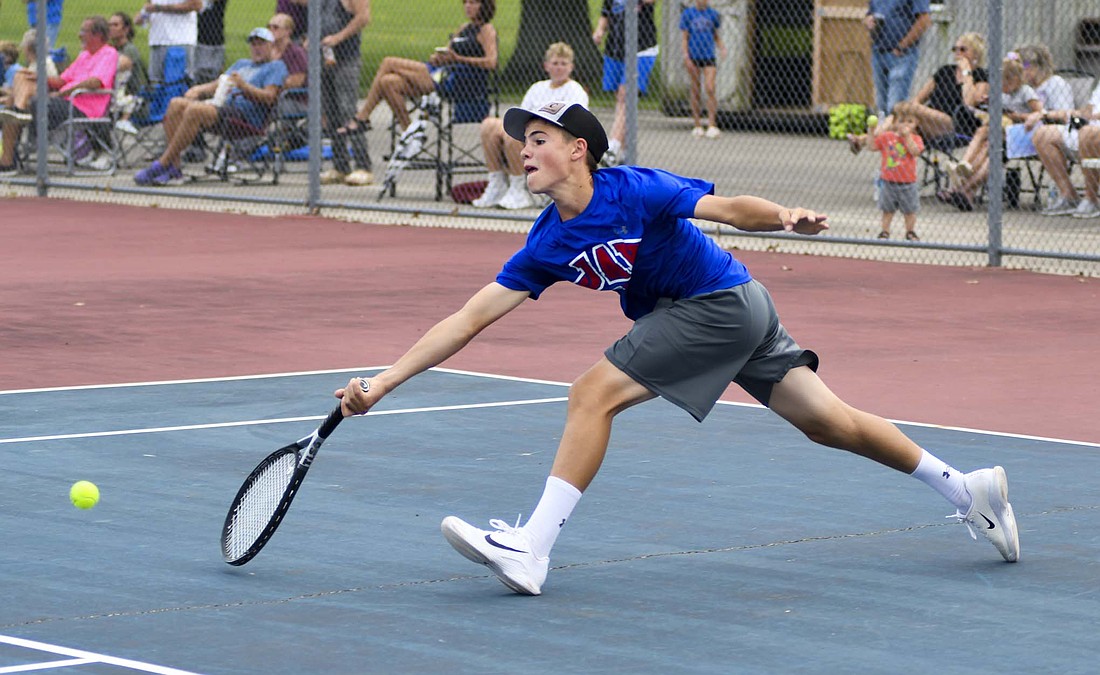 Jay County High School’s Paul Dirksen reaches to hit a tennis ball before it reaches the court during Tuesday’s 4-1 loss against Alexandria-Monroe. Dirksen pulled off the sole win for JCHS at No. 1 singles, beating Ryan Long 6-2, 6-2. (The Commercial Review/Andrew Balko)
