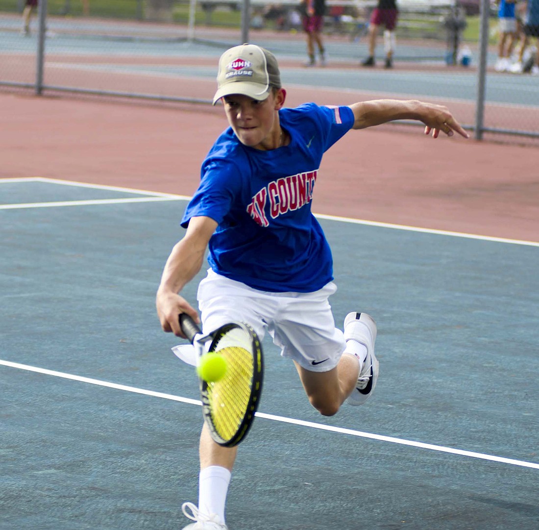 Jay County High School’s No. 2 singles player Henry Dirksen runs up on a ball to hit a one-handed backhand during his match against Alexandria-Monroe’s Austin Webb on Tuesday. The freshman picked up his first win on Monday against Madison-Grant. (The Commercial Review/Andrew Balko)