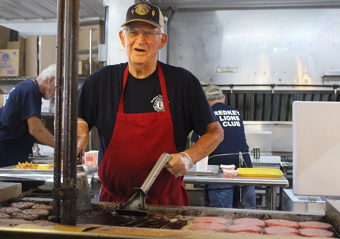 Sonny Champ looks up from grilling hamburgers Thursday morning at the Lions Club stand at Jay County Fairgrounds. A 90-year-old Redkey resident, Champ has been cooking the stand’s “Lion Burgers” during events such as the Tri-State Antique Gas Engine and Tractor Show for decades. (The Commercial Review/Bailey Cline)