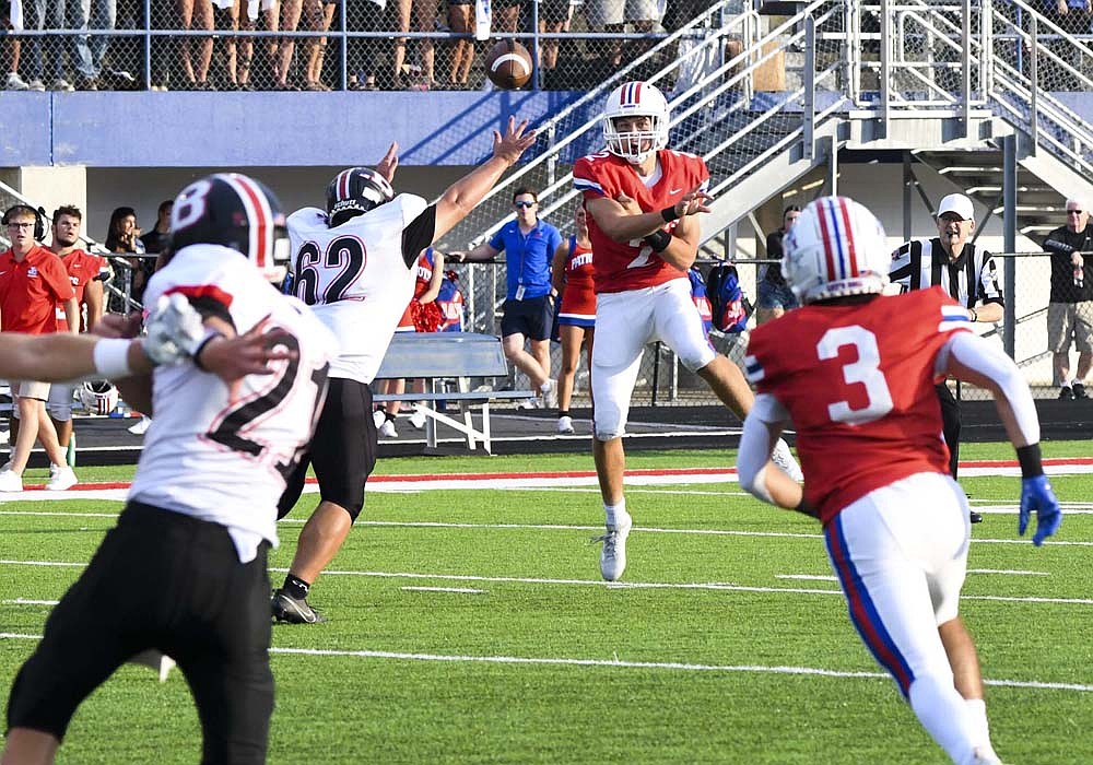 Jay County High School quarterback Nick Laux slings a pass toward Brady Jetmore while receiving pressure from Blackford’s Clayton Heflin on Friday night. After a slow start, Laux ended up completing 9-of-12 passes for 203 yards and threw for three touchdowns in the 56-6 win over the Bruins. (The Commercial Review/Andrew Balko)