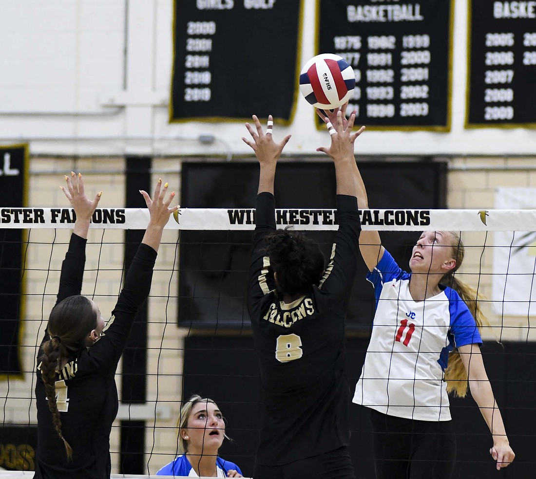 Mya Kunkler of the Jay County High School volleyball team reaches up to tap a ball over the block of Winchester’s Molly Barker (4) and Lilyana Mayberry (8). Kunkler finished the match with five kills as JCHS beat the Golden Falcons 25-21, 18-25, 25-12, 25-19. (The Commercial Review/Andrew Balko)