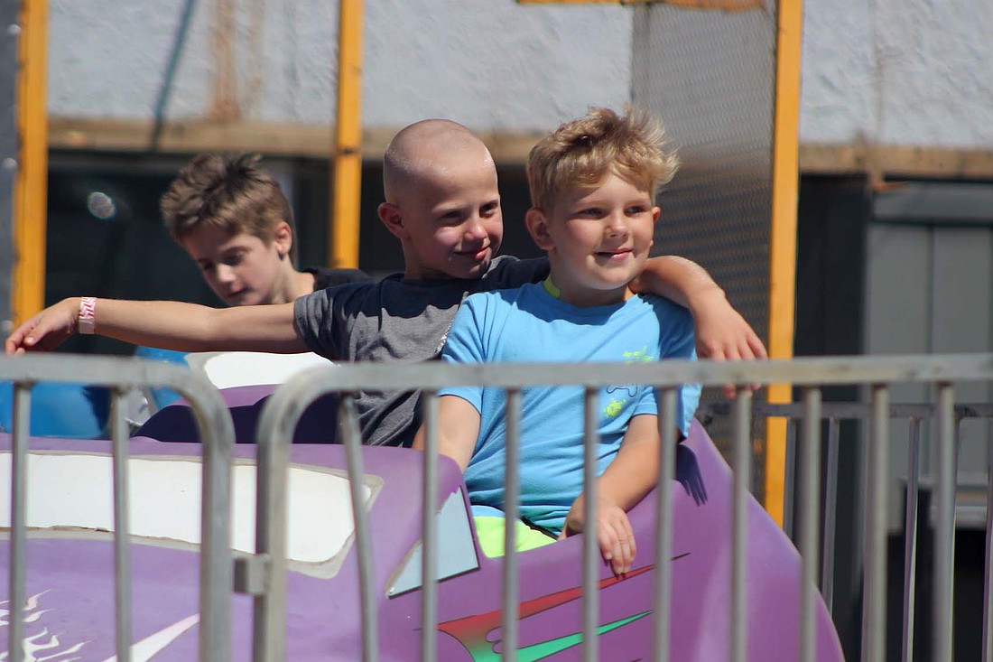 Logan Schoenlein, 9, and Dawson Stallsmith, 9, of Portland look at Stallsmith’s mother while whizzing around on a ride at Montpelier Jamboree on Saturday. (The Commercial Review/Bailey Cline)