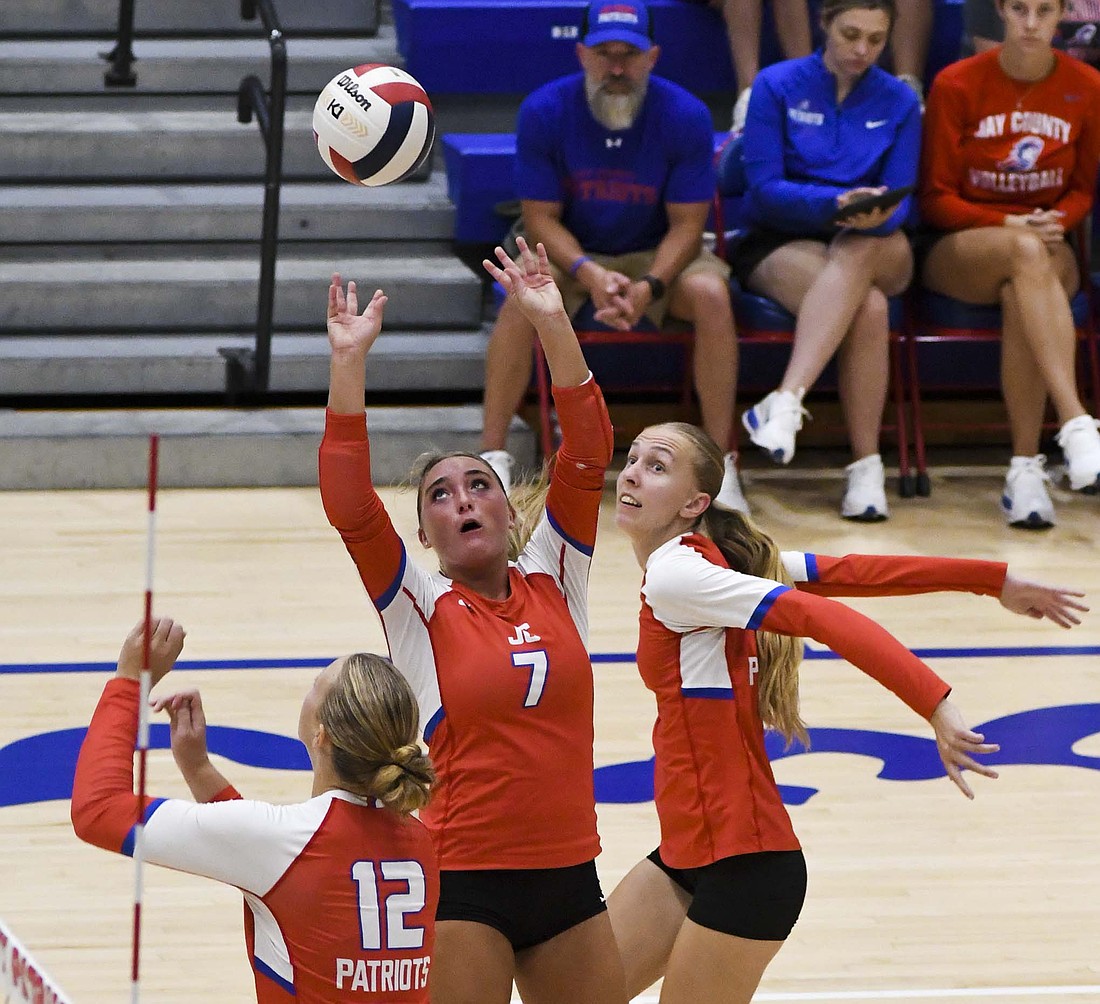 Jay County High School’s Paisley Fugiett (7) sets a ball as middle blockers Maria Hemmelgarn (12) and Mya Kunkler run to the net. The two middles combined for 10 kills and eight blocks to help lead the Patriots past Adams Central 25-16, 25-20, 25-18. (The Commercial Review/Ray Cooney)