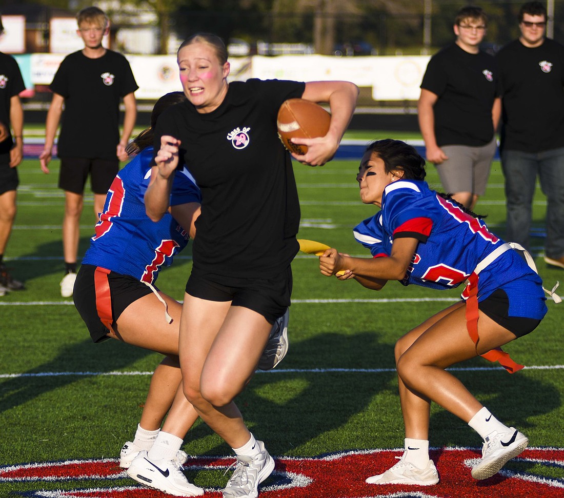 Jay County High School senior Aixa Lopez (left) grabs freshman Carsyn Schwieterman’s flag Wednesday during the opening powderpuff football game of the evening as part of Spirit Night activities. Assisting on the “tackle” is Alexis Sibray. The seniors went on to defeat the juniors in the powderpuff championship game. (The Commercial Review/Ray Cooney)
