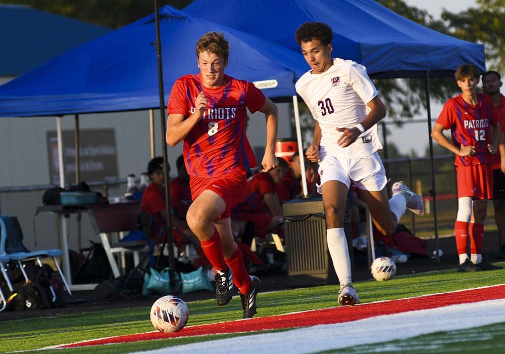 Max Klopfenstein of Jay County High School chases a ball down the sidelines against Malachi Lavine of the Bellmont Braves during the second half Thursday. The host Patriots scored three times in the first 21 minutes, including a pair of 25-yard shots, on the way to halting a four-game losing streak with a 3-1 victory. (The Commercial Review/Ray Cooney)