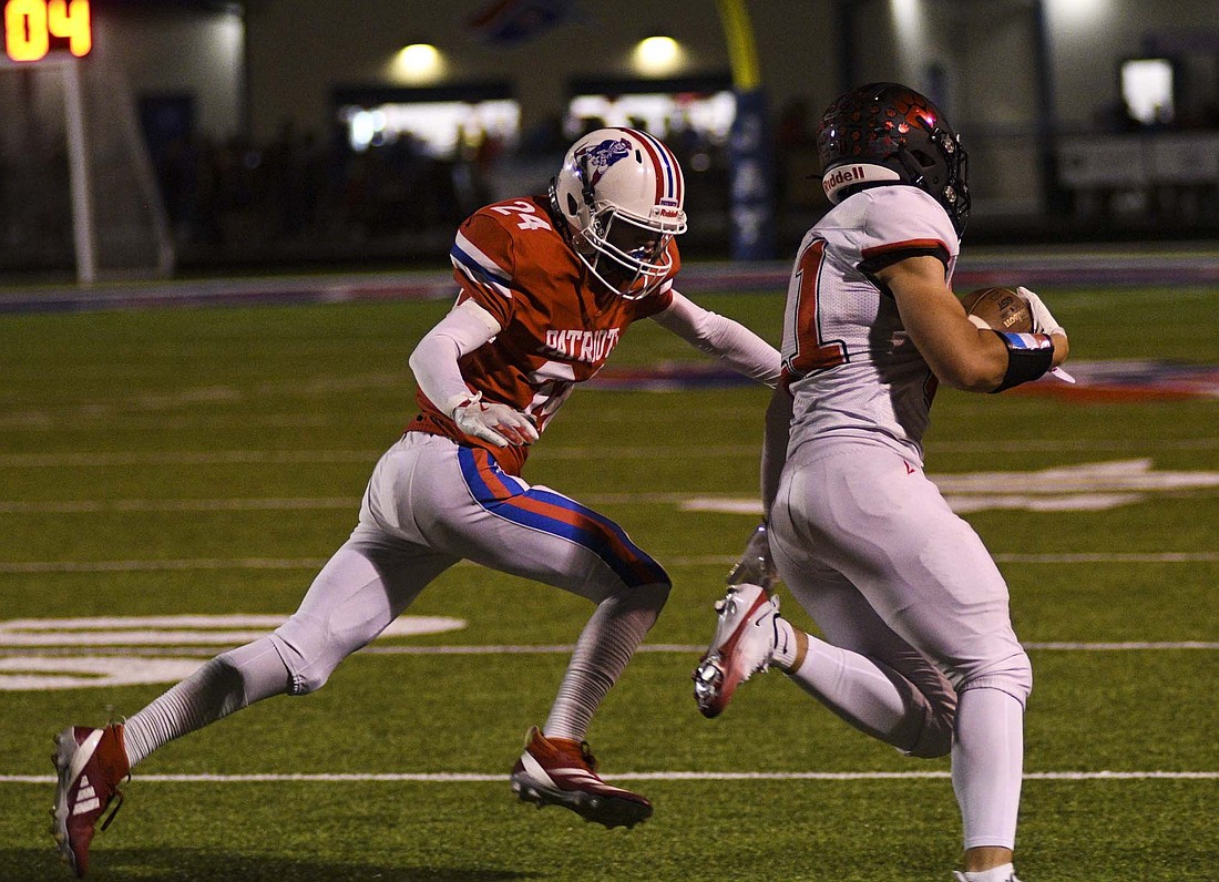 Kaiden Reynolds of Jay County tries to chase down Bluffton’s Aaron Streveler during the first half Friday night. The Patriots were outgunned 432-161 on the game as they suffered their third shutout of the season. (The Commercial Review/Ray Cooney)
