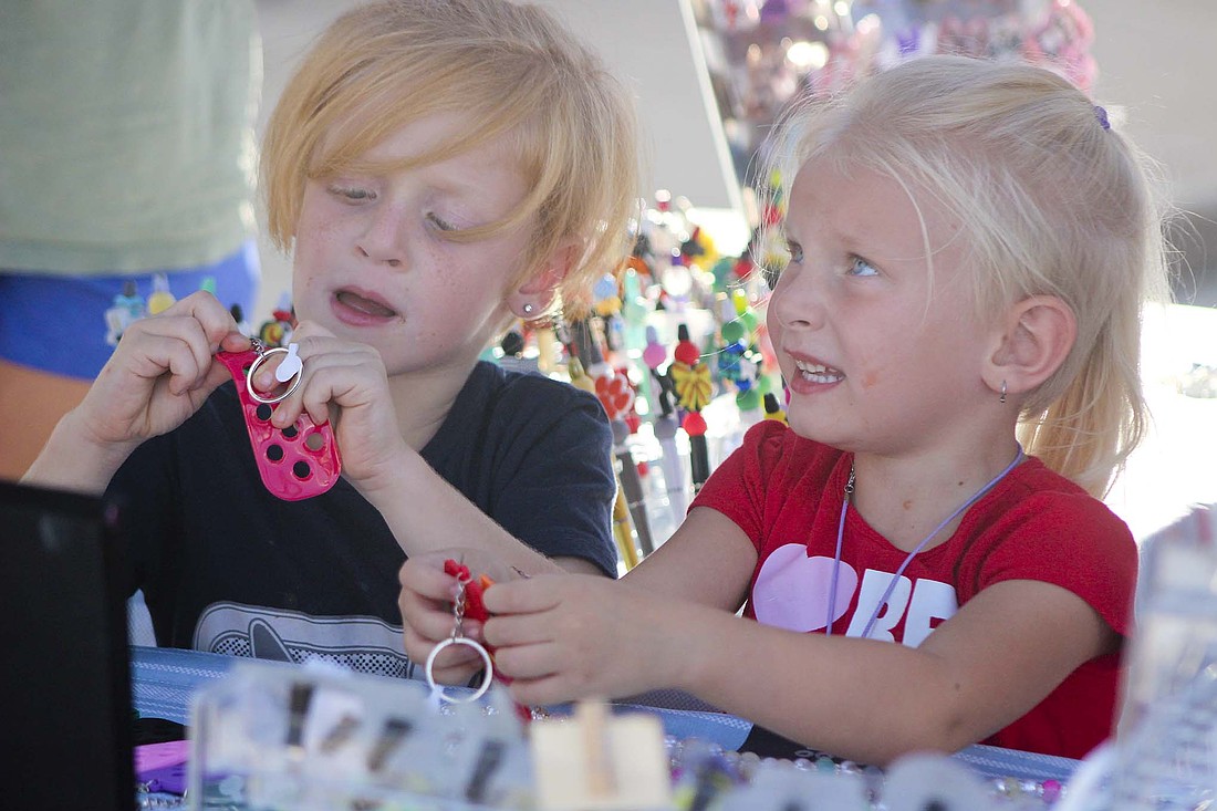 Jack, 6, and Sarene, 5, Stanton look at keychains for sale Saturday during the Portland Main Street Fall Festival. The event featured various food and craft vendors, as well as a free pumpkin painting activity. (The Commercial Review/Bailey Cline)