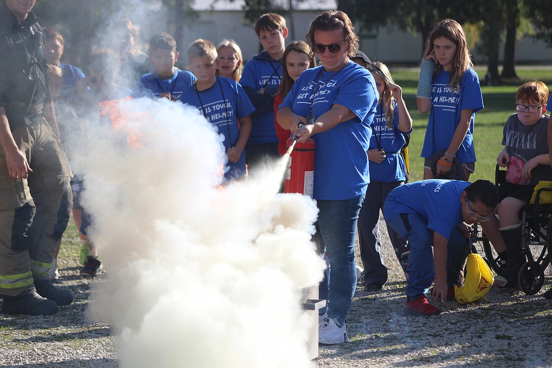 East Jay Elementary fifth grade teacher Jessica Steed puts out a controlled fire during a demonstration Thursday at Jay County Fairgrounds. Classes visited the fairgrounds for Jay County Safety Day, learning about safety protocols from various agencies, including Portland Fire Department and Jay Emergency Medical Service. (The Commercial Review/Bailey Cline)