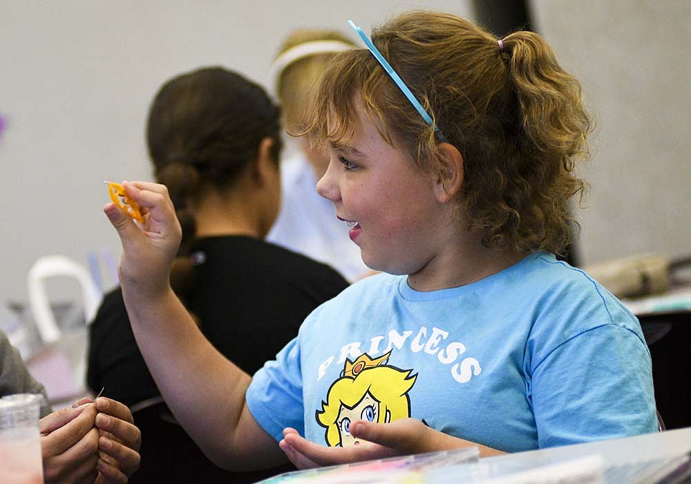 Ten-year-old Mackenna Cramer grins while showing her mom Kylie a bead she selected to add to a necklace during Jay County Public Library's “Get Crafty, Swifties!” event Thursday evening. Attendees were treated to pink punch, sparkly cat ear headbands and a variety of craft options. (The Commercial Review/Ray Cooney)