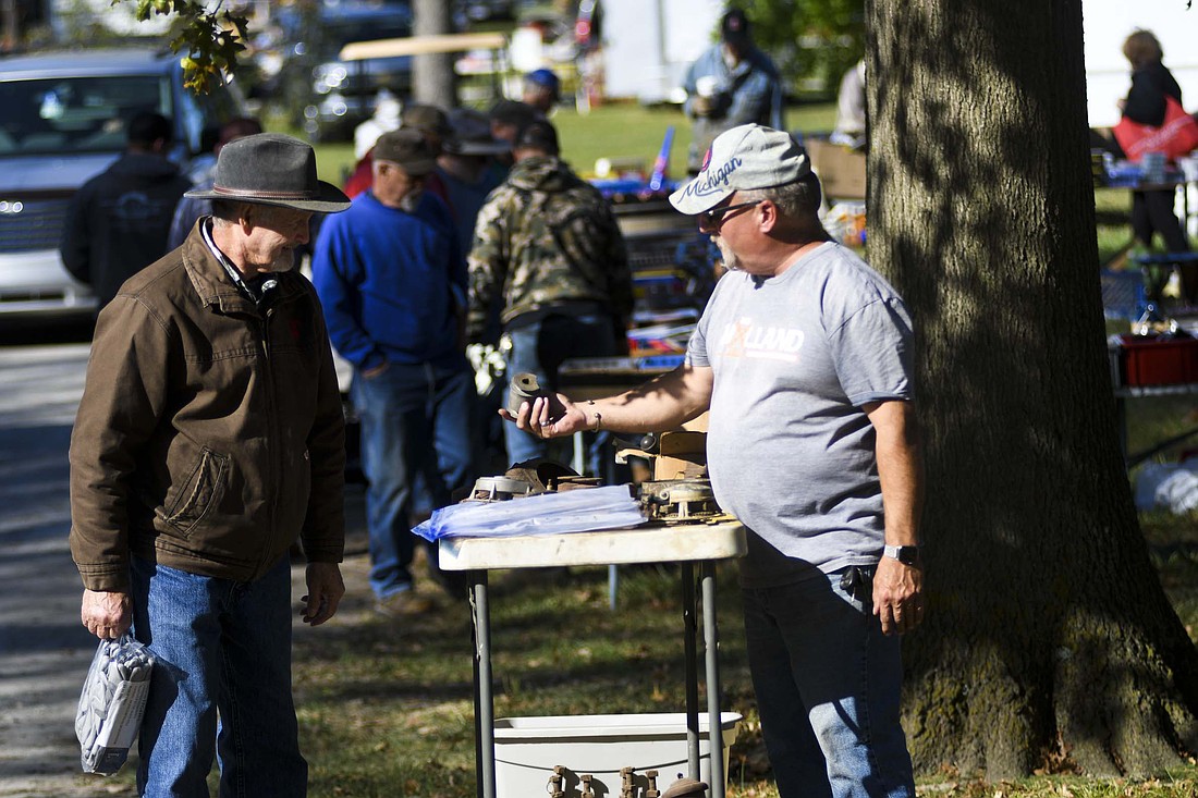 Kevin Johnson of Pendleton shows a part to potential customer Joel Taylor of Redkey on Thursday morning during the first day of the Tri-State Gas Engine and Tractor Association’s Fall Swap and Sell Meet at the Tri-State grounds. Johnson is a regular at Tri-State’s fall show and has attended the spring swap meet, but this marks his first visit to the fall swap meet. He explained that he has shifted priorities and is trying to be more of a seller than a buyer. The swap meet continues today and Saturday at the Tri-State grounds, 1010 N. Morton St., Portland. Admission is $5. (The Commercial Review/Ray Cooney)