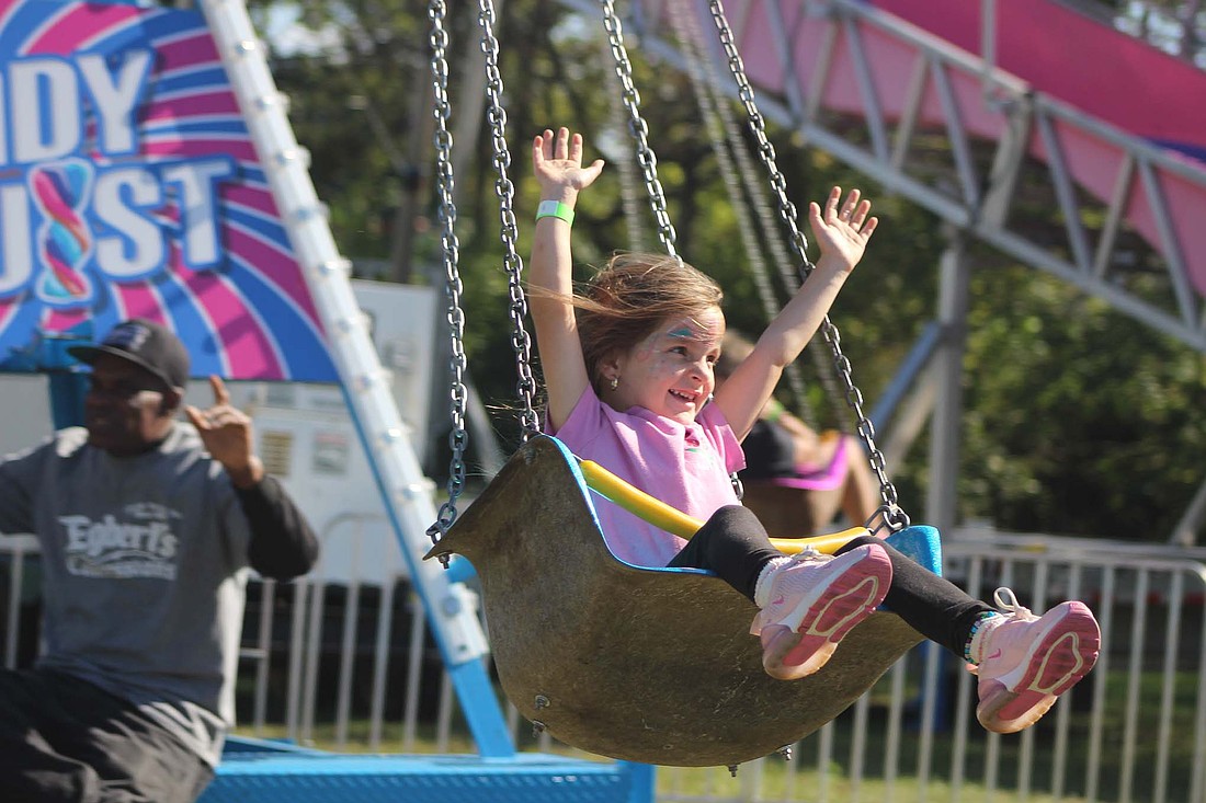 Ellee Scott, 5, Ridgeville, raises her hands in the air on the swings Saturday during the Ridgeville Fall Festival. The event offered carnival rides, music, food trucks and vendors in downtown Ridgeville. (The Commercial Review/Bailey Cline)