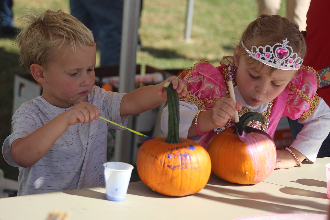 Rhiot Ray, 4, Pennville, paints pumpkins with cousin Benelli Ellis, 5, Portland, during the Pennville Pumpkin Festival on Saturday. (The Commercial Review/Bailey Cline)