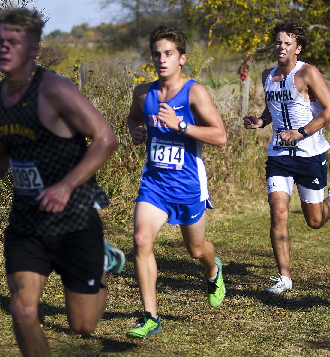 Jay County High School freshman Grant Glentzer runs between Carson Laux of South Adams and Elijah Jacob of Norwell during Saturday’s sectional cross country meet at Taylor University. Glentzer joined teammates Caleb Garringer and Max Klopfenstein in qualifying for Saturday’s regional meet at Huntington North. (The Commercial Review/Ray Cooney)
