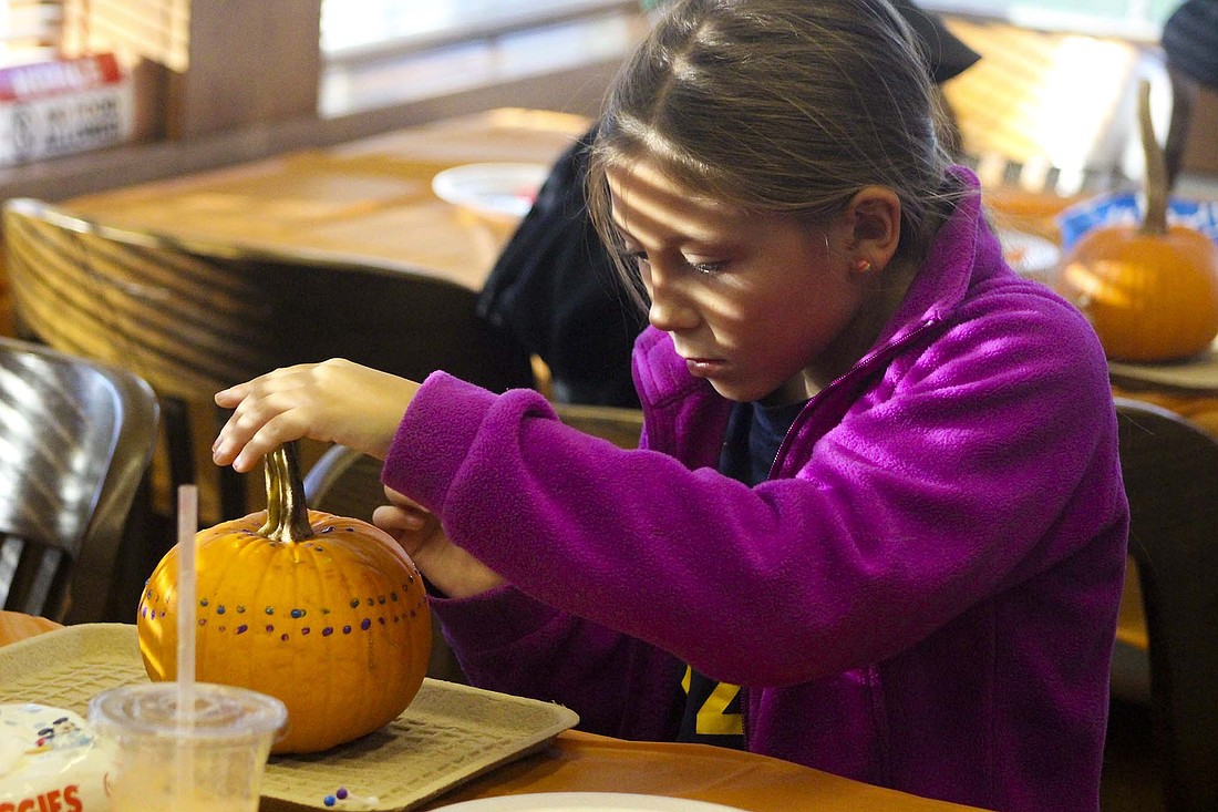 Skye Ingram, 9, Portland, dots purple and blue paint around her pumpkin Thursday at Jay County Public Library. The library offered various pumpkin-themed activities for families. (The Commercial Review/Bailey Cline)