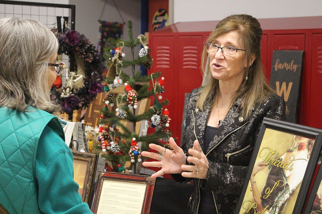 Author Monica Koldyke Miller (right) shares details about her books Saturday with Nancy Rismiller of Versailles, Ohio, during The Delts’ Holiday Crafts and Gifts Show. (The Commercial Review/Bailey Cline)