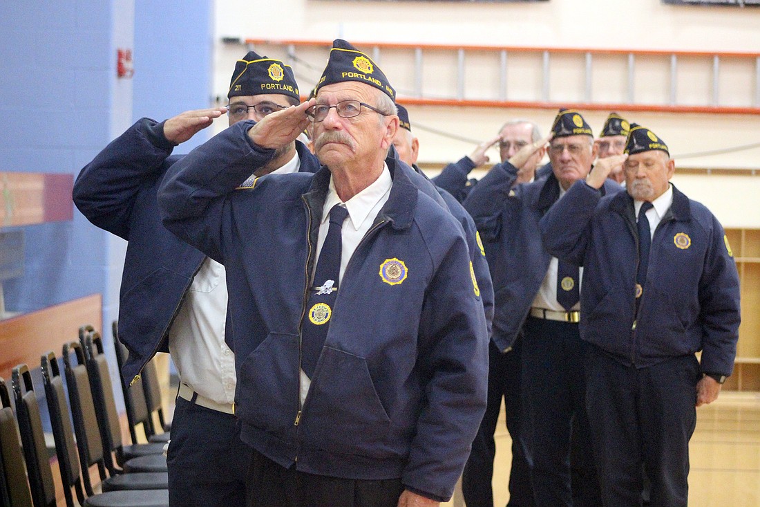 Steve Bailey (foreground) and Anthony Campofiore of Portland salute Tuesday during the Veterans Day service coordinated by American Legion Post 211 at Jay Community Center. “Only about 6% of American adults today have served in the military, yet it’s a small and talented group that enables our communities to function,” said pastor Darrell Borders. (The Commercial Review/Bailey Cline)