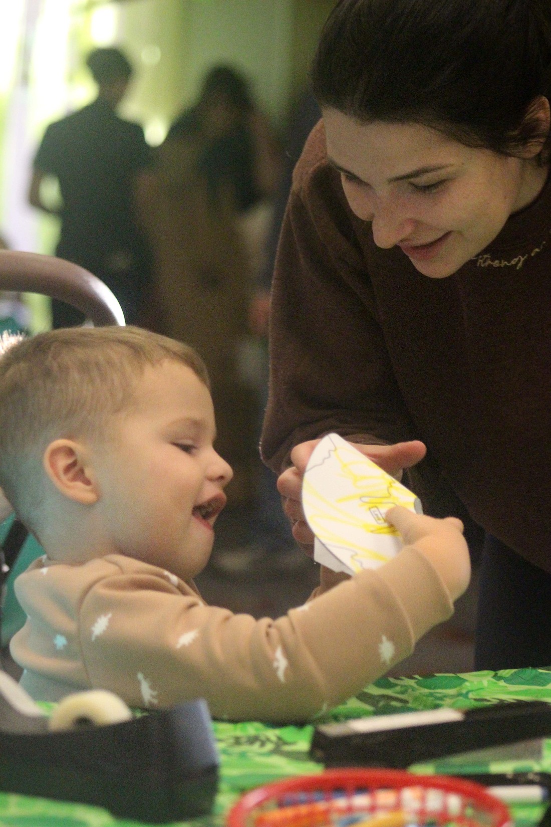 Three-year-old Grayson Nusbaumer and mother Chloe Nusbaumer of Portland make a paper volcano during Jay County Public Library’s interactive dinosaur experience last week. (The Commercial Review/Bailey Cline)