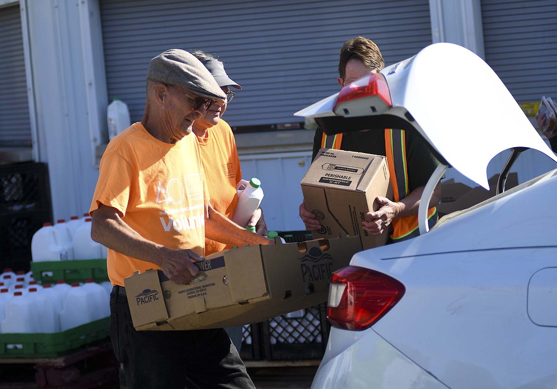 Volunteers including Daniel Chase (foreground) load food into the trunk of a vehicle during a Second Harvest Food Bank and United Way of Jay County tailgate food distribution session in October at Jay County Fairgrounds. Additional food tailgates have been implemented to help after federal food assistance programs were paused early this month and United Way of Jay County is partnering with other local organizations on a fundraising drive. (The Commercial Review/Ray Cooney)