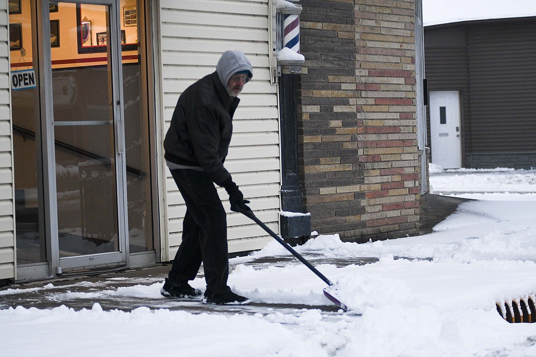 Rick Shreve clears snow from the sidewalk in front of his business, Hair Studio, 303 N. Meridian St., Portland, on Tuesday morning. About 2 inches of snow fell Monday evening, leading to Jay School Corporation calling off classes for the second day in a row Tuesday. (The Commercial Review/Ray Cooney)