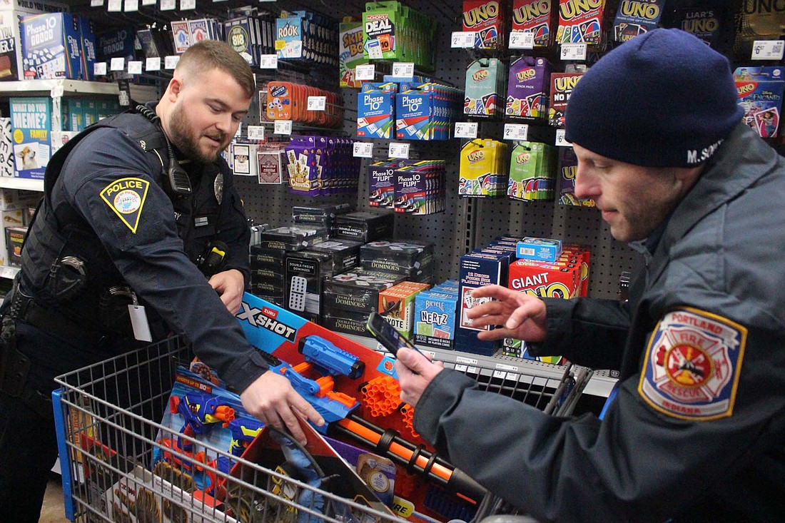 Holiday festivities continued this weekend with the Portland police and fire departments holding their Shop with a Badge day on Sunday and the Fort Recovery Local Schools choirs performing their Christmas concert Sunday evening. Portland police officer Mitchell Rigby (left) and Portland firefighter Mitch Southworth add gifts for children to the cart and calculate costs at Walmart. Local responders shopped with children this weekend, allocating $125 per child. (The Commercial Review/Bailey Cline)