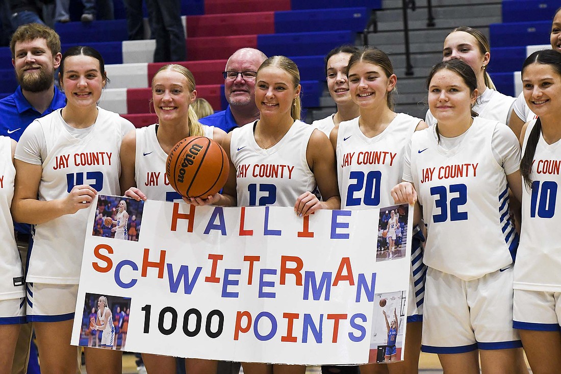 Hallie Schwieterman (holding ball) of the Jay County High School girls basketball team poses with teammates after surpassing 1,000 career points in Tuesday's 74-45 win over the Concordia Cadets. Flanking Hallie Schwieterman (from left) are Charlee Peters, Karsyn Schwieterman, Claudia Dirksen, Alivya Schwieterman and Raylah Newton. (The Commercial Review/Ethan Oskroba)