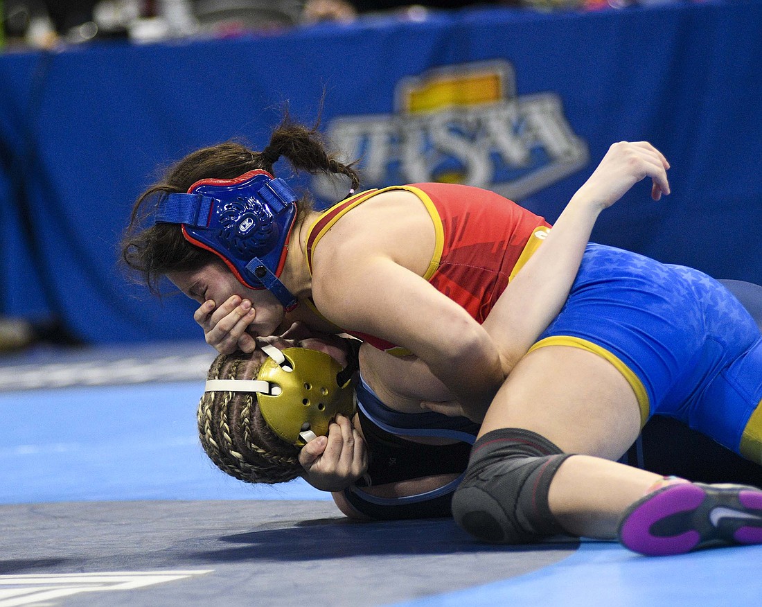 Katie Rowles of Jay County gets a hand to the face while trying to hold down Aniah Delgado of Perry Meridian for a pin in their seventh-place match at 100 pounds during Friday’s state finals. Rowles scored the pin in 40 seconds to finish her career with a victory. (The Commercial Review/Ray Cooney)