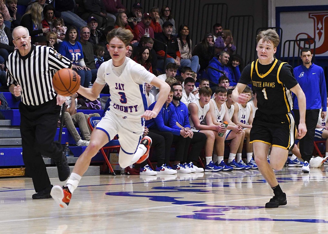 Gabe Overton of the Jay County High School boys basketball team sprints past South Adams’ Derek McKean after a steal during the Patriots’ 53-39 win over the visiting Starfires on Friday. Jay County forced 19 South Adams turnovers while only committing four of its own. (The Commercial Review/Ethan Oskroba)