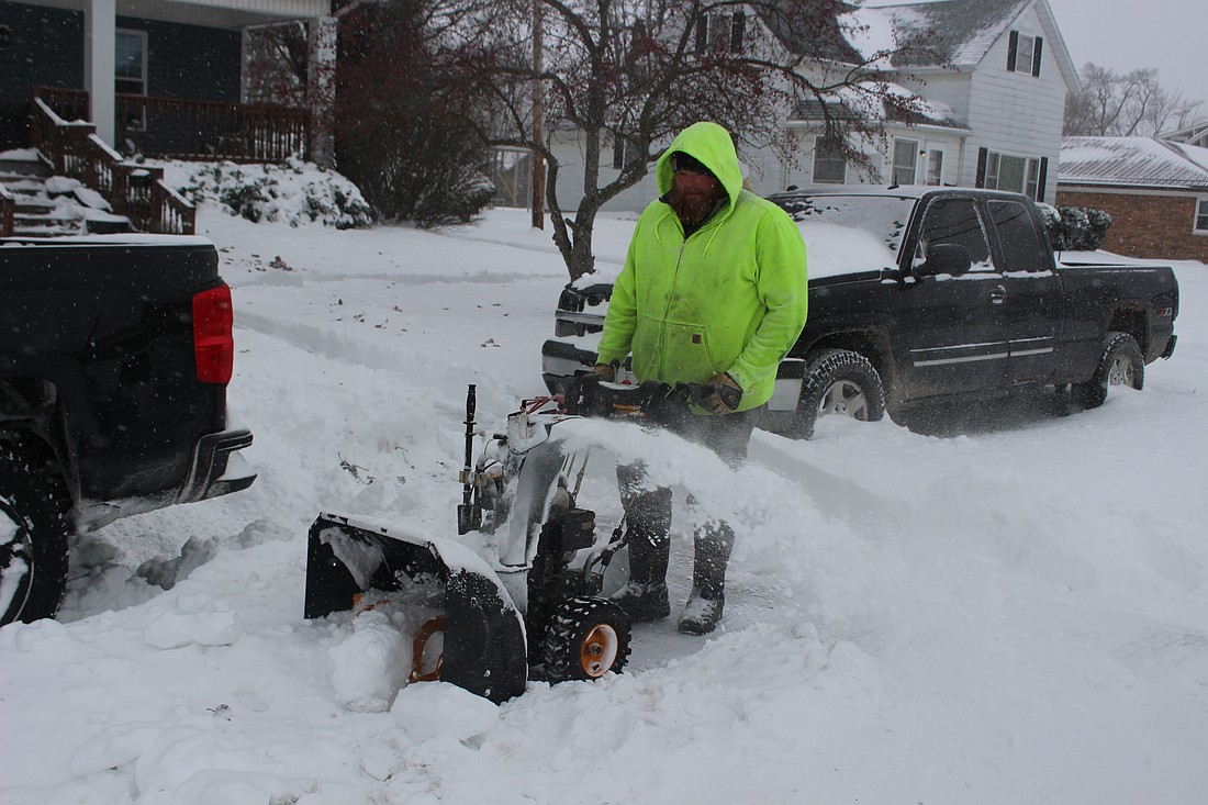 Chris Nibarger uses his snow blower to clear the sidewalks and road at the intersection of Pleasant and Main streets in Sunday. (The Commercial Review/Bailey Call)