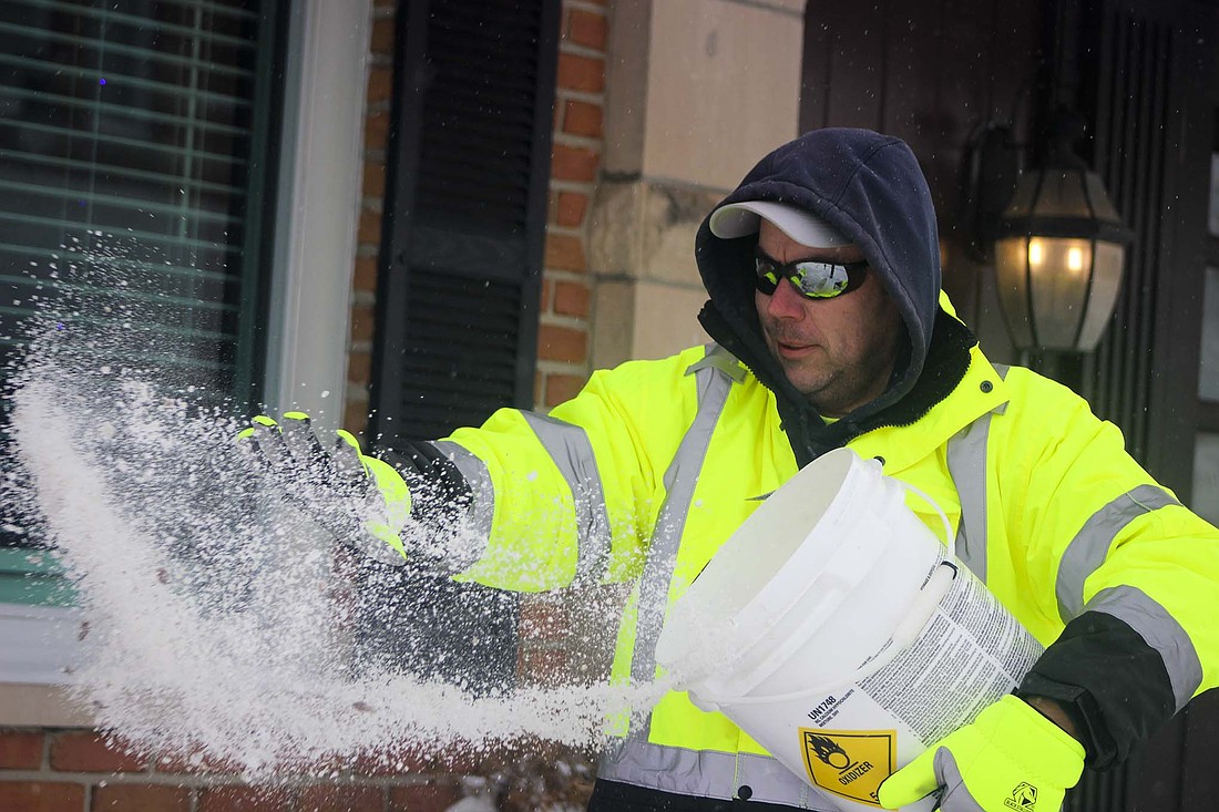 Portland Street Department superintendent Matt Shauver spreads salt on the sidewalk Monday morning in front of Portland City Hall. City and county crews were out throughout the day Sunday and again Monday in an effort to clear snow from roads and streets after 11.5 inches of snow fell Saturday and Sunday. With winds forecast to gust to 30 mph on Monday night, local officials expressed concern that drifting would continue to cause travel problems. (The Commercial Review/Bailey Call)